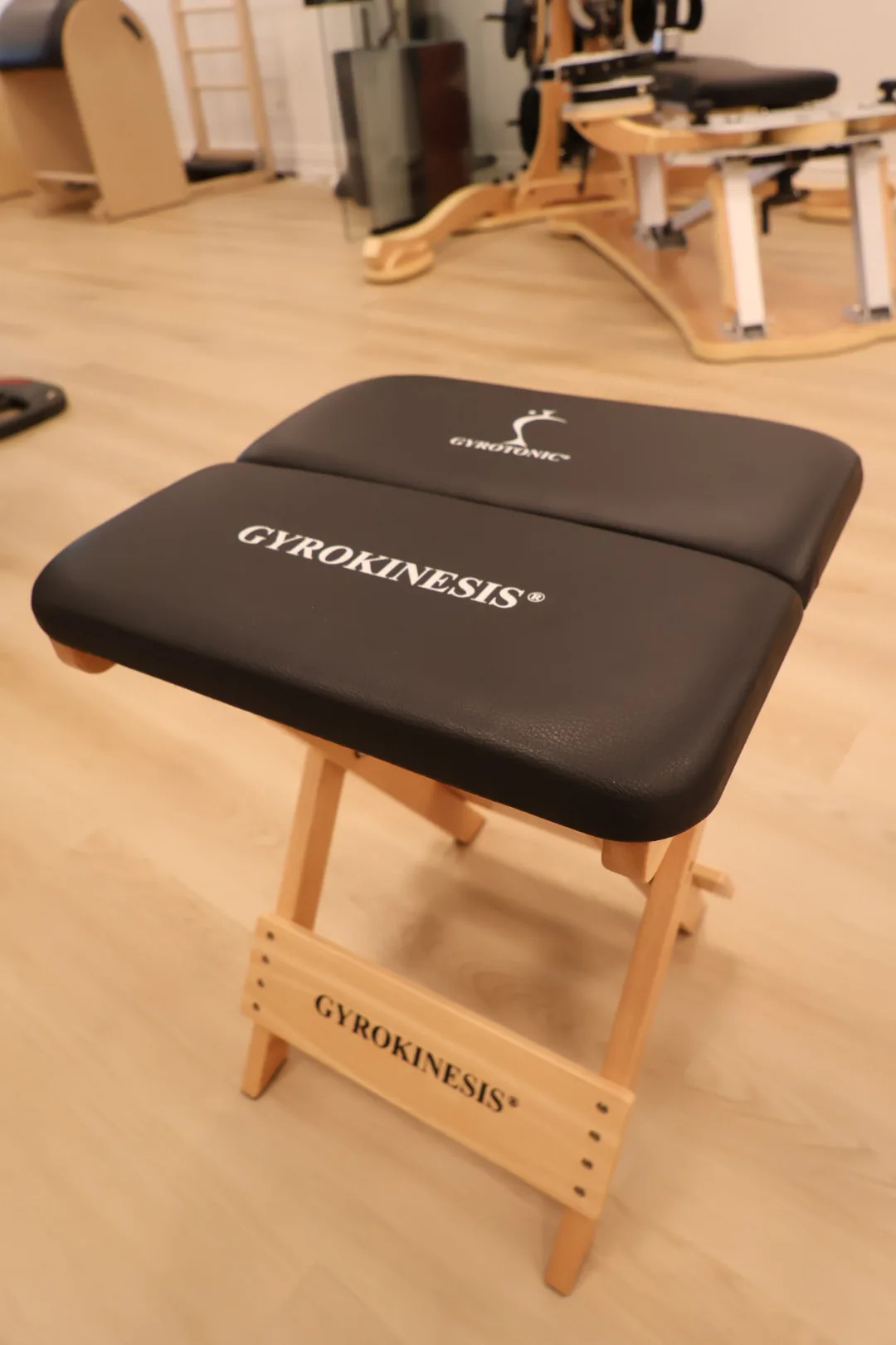 Padded GYROKINESIS® stool used for seated movement practice.