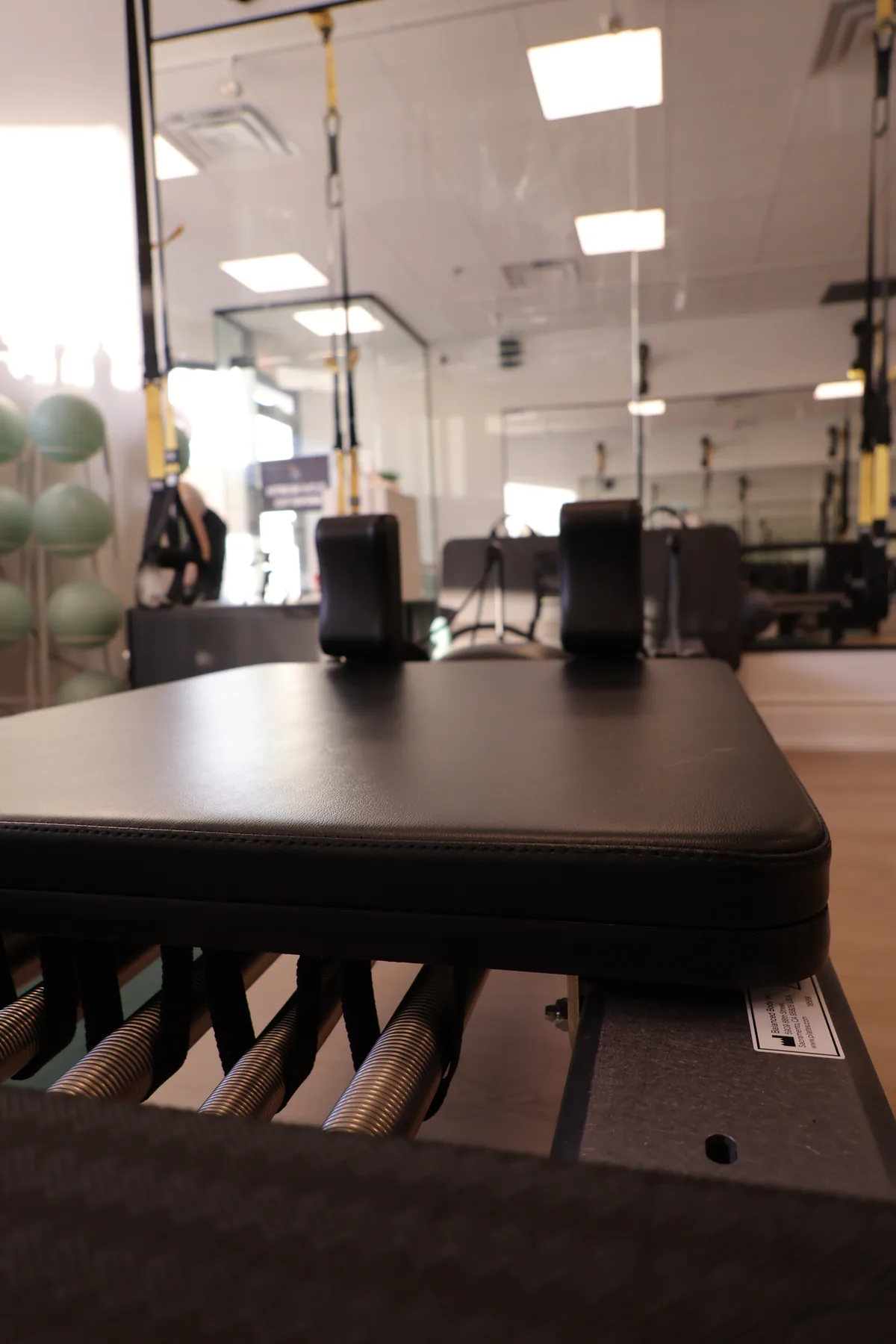 Close view along a Pilates reformer carriage in the first studio room.